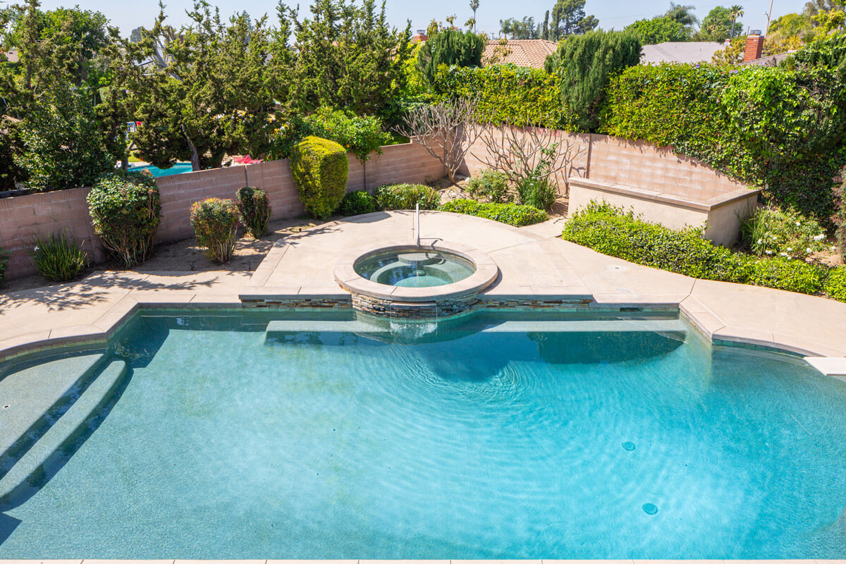 homepage2 A backyard pool surrounded by lush greenery, perfect for relaxation and enjoyment on a sunny day.