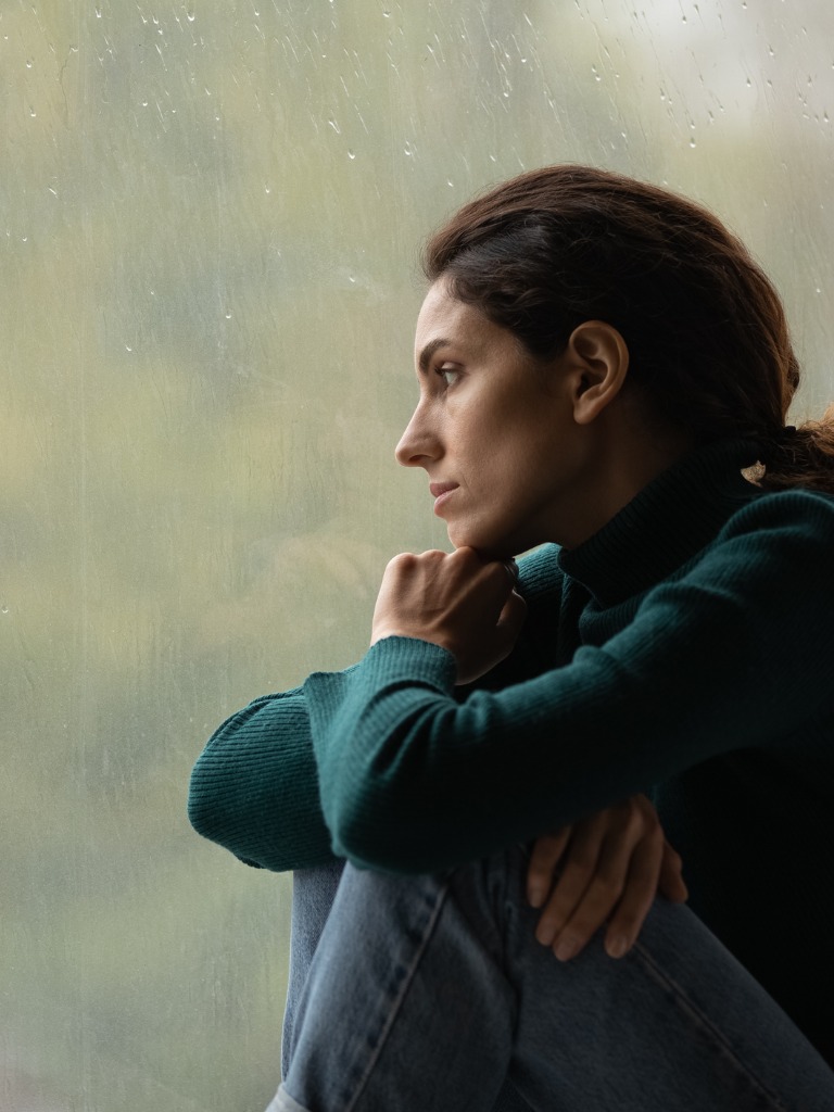 depressed looking woman, staring out at the rain - bulimia