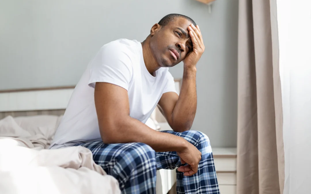 Adult sitting quietly by a window at home, looking preoccupied