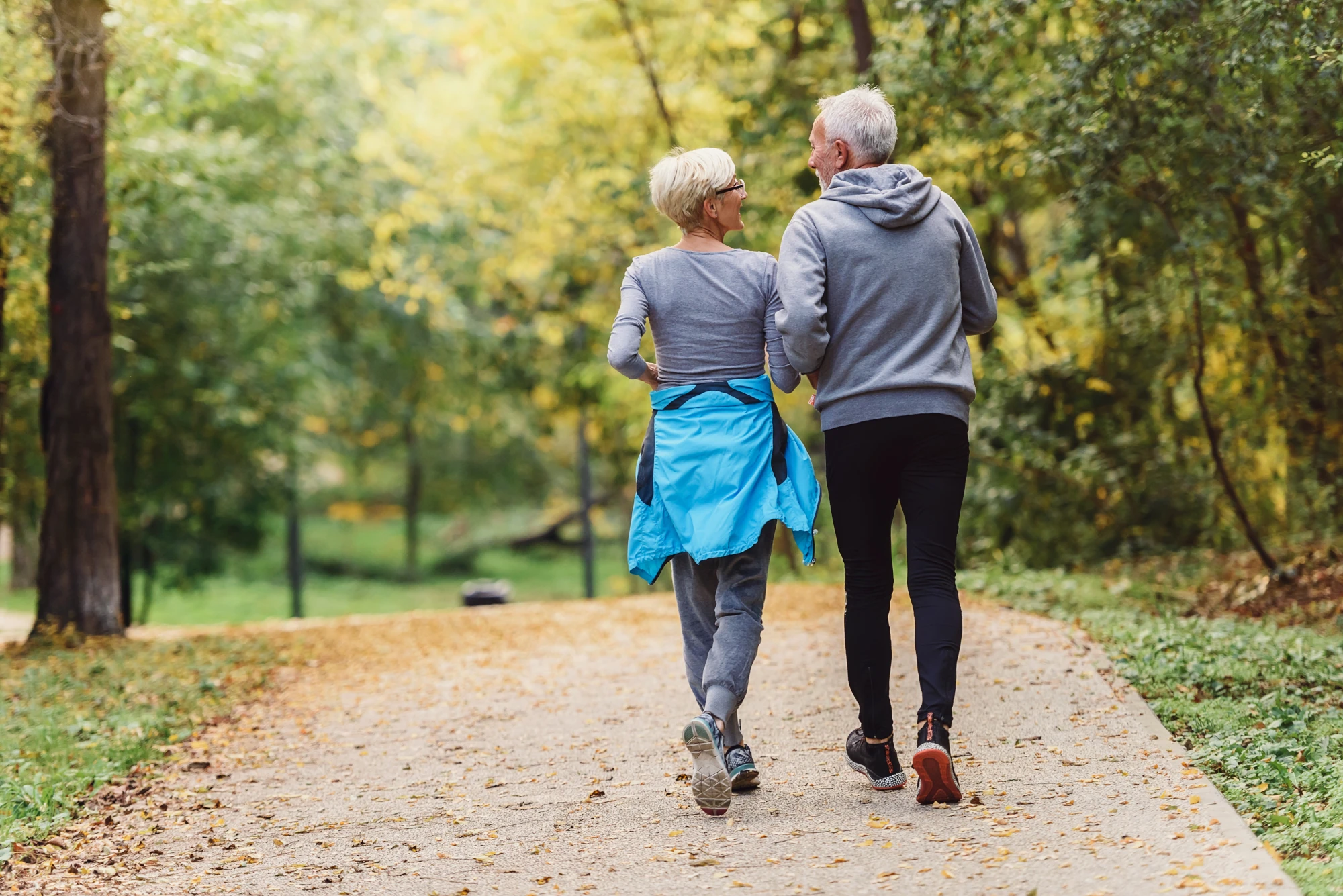 Two people walking side by side on a quiet path outdoors, talking